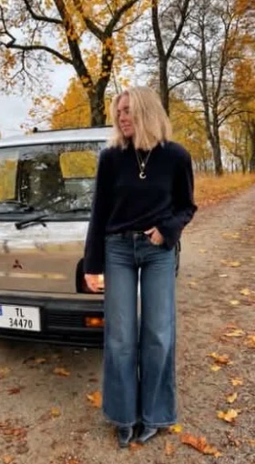 Charlotte ved en sølvgrå Mitsubishi Minicab i høstløv